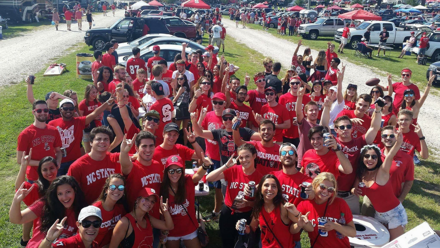 Large group of NC State students in parking lot at a tailgate