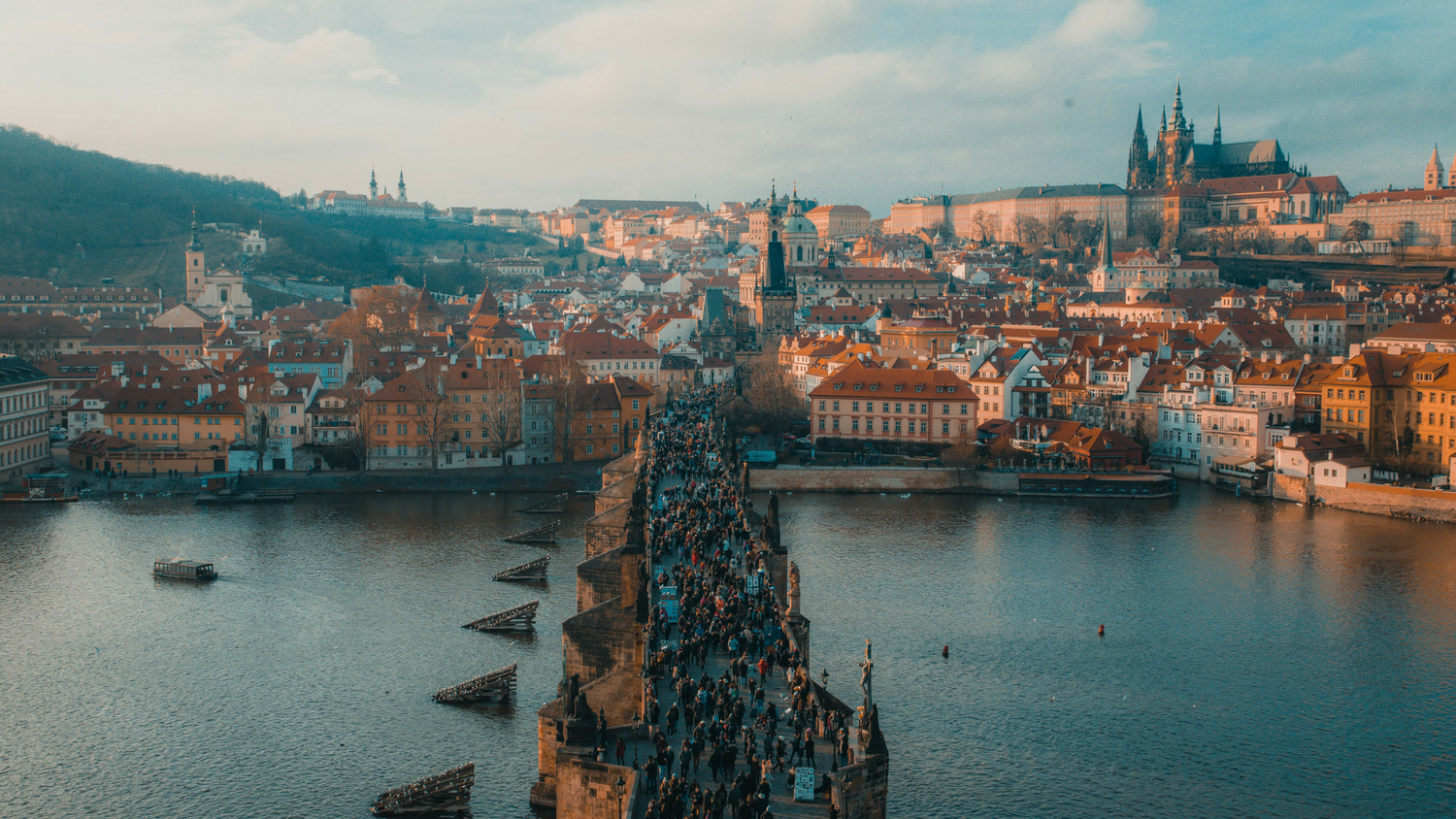 people on bridge with Prague cityscape