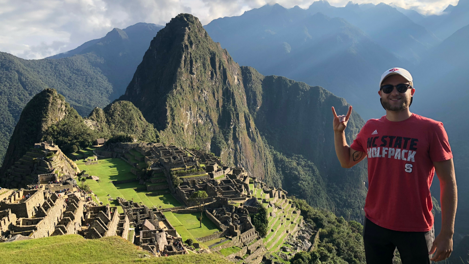 male student wearing NC&#160;State shirt with Machu Picchu in background
